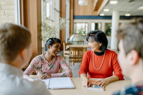 Faculty member sitting with student in the library.